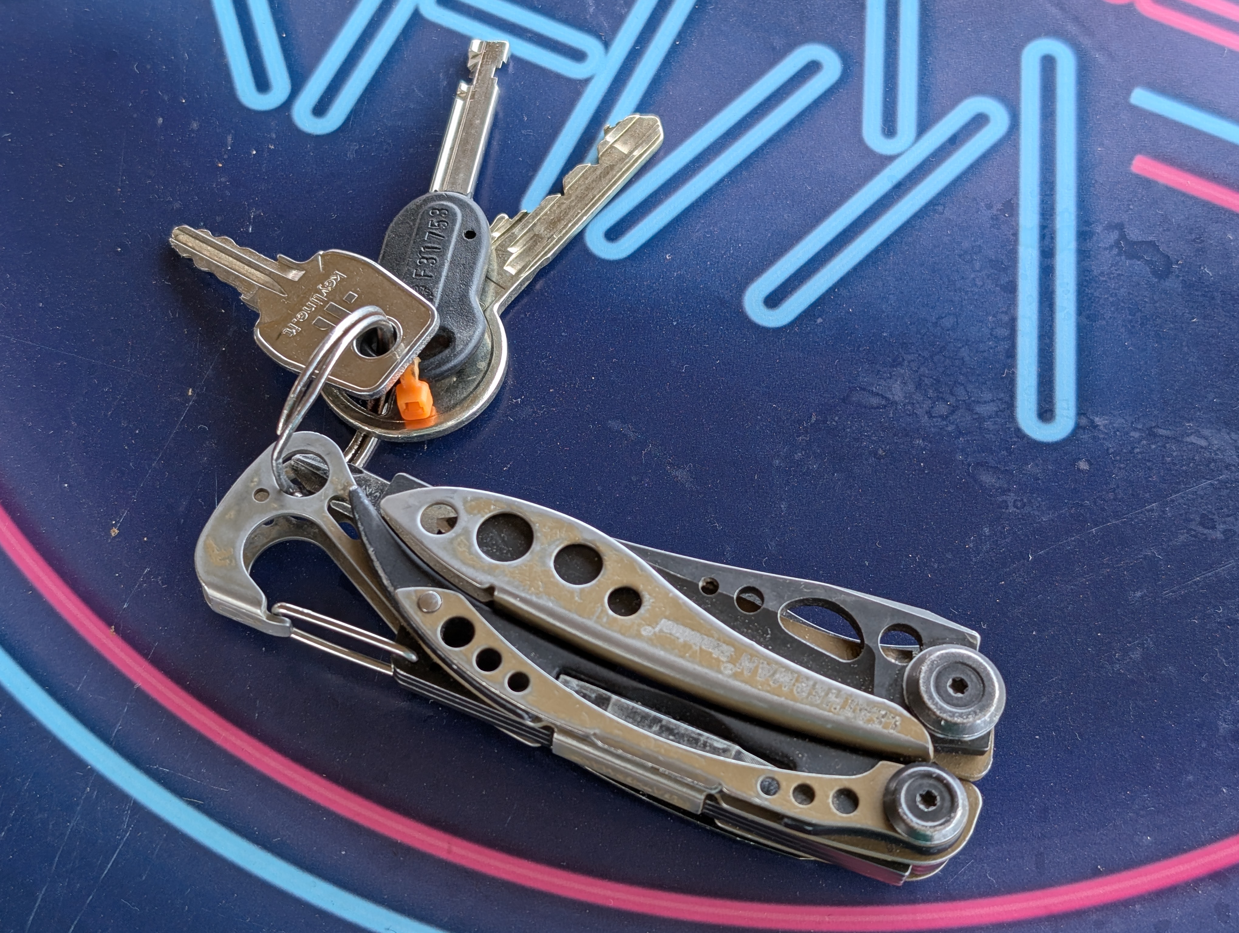 my keys and worn green leatherman tool sitting on a bar table