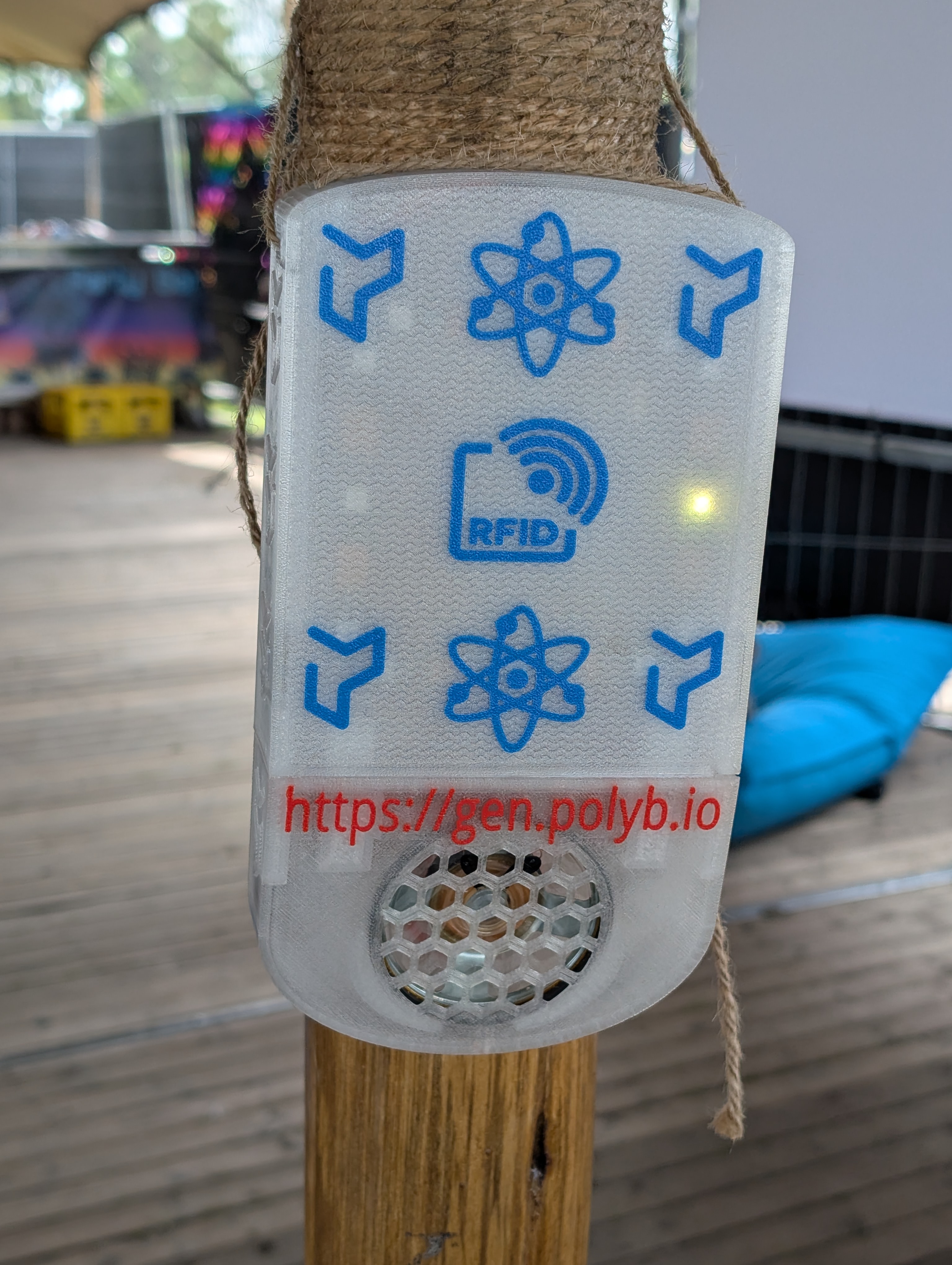a white plastic device attached to a post. there are blue symbols on the device, like the planetary model of an atom and RFID