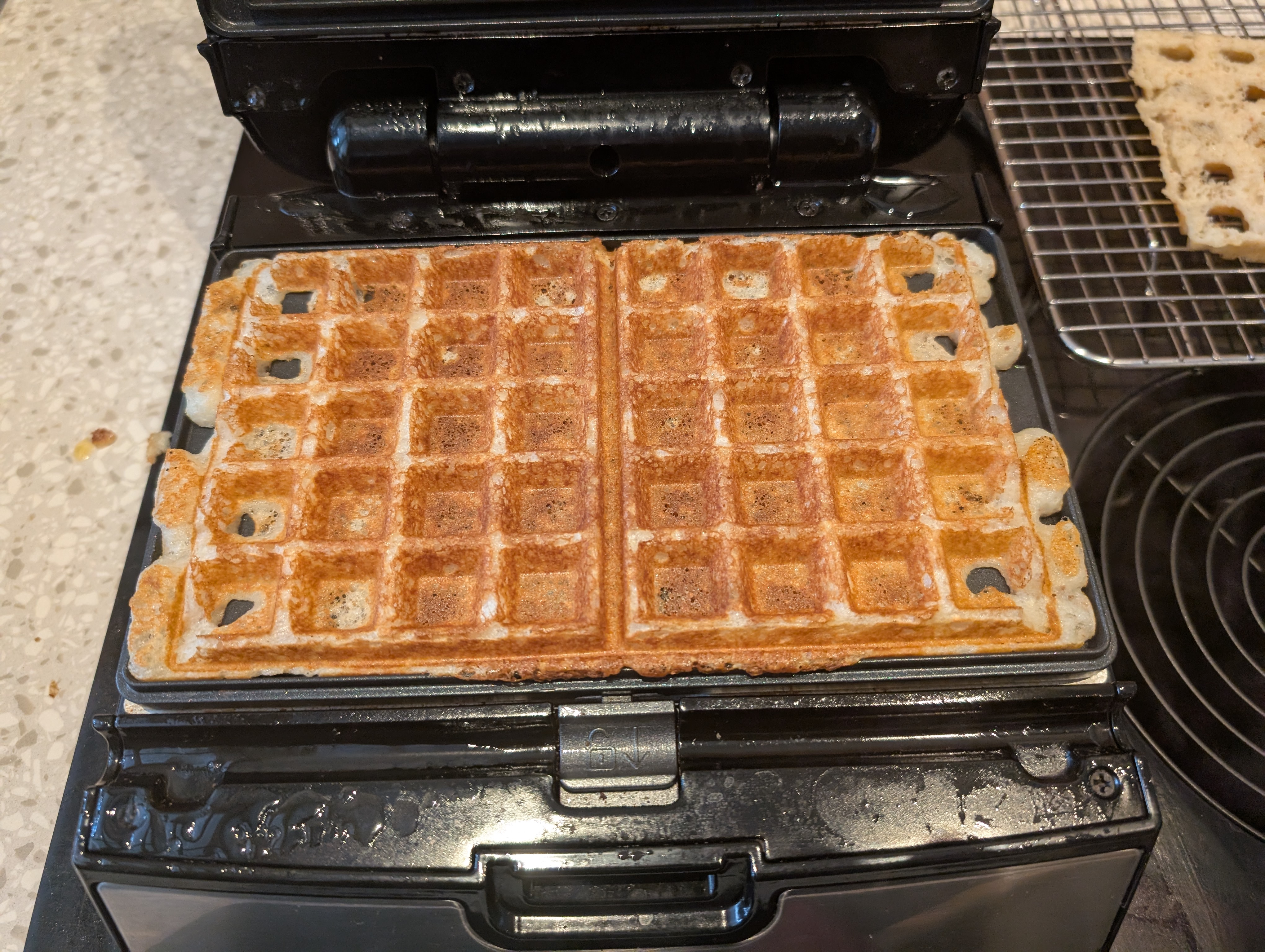 a closeup like the first picture, but showing a golden brown perfectly cooked waffle with a perfect, the grid visible in an almost emoji-like shape